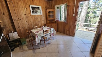 Un intérieur en bois comprenant une table à manger, des chaises, un buffet et une fenêtre avec des rideaux.