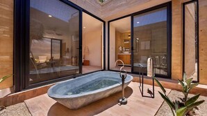 Een moderne, openlucht badkamer met een vrijstaand bad, grote glazen deuren en uitzicht op het interieur.