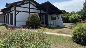 A traditional Japanese-style house with a black and white exterior, a small garden with pink flowers, and a clear blue sky. - Gîte Jean de Nasse - CASTETS (CASTETS)