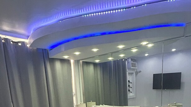 Un dormitorio moderno con una cama grande, mesitas de noche, un televisor de pantalla plana e iluminación ambiental.
