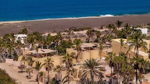 Ein Küstenresort mit mehreren Gebäuden, Palmen und einem Strand im Hintergrund.