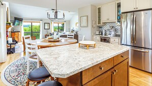 A kitchen with a large island, stainless steel appliances, and a dining area with a view. - Spacious 3BR*Ensuites | Hot Tub*Fire Pit*Game Room*Coffee Bar*Stunning Sunsets! (Galena)