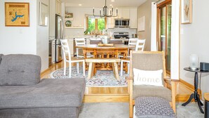 A modern kitchen with a central island, white cabinetry, and a dining area with a round table and chairs. - Spacious 3BR*Ensuites | Hot Tub*Fire Pit*Game Room*Coffee Bar*Stunning Sunsets! (Galena)