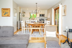 Une cuisine moderne dotée d’un îlot central, de meubles blancs et d’un coin repas avec une table ronde et des chaises.