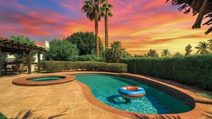 A swimming pool with a curved design, surrounded by palm trees and a pergola. - Coachella Casa Spanish-Style Oasis with Pool in Indio (Indio)