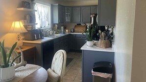 Una cocina moderna con armarios oscuros, una isla central y un comedor con mesa y sillas.