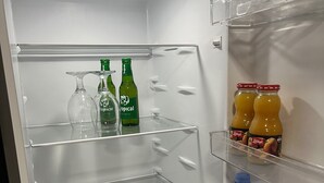 An open refrigerator with shelves containing bottles of Tropicana orange juice, Aquaviva mineral water, and two green bottles of a beverage.
