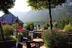 An outdoor patio with a table and chairs, surrounded by lush greenery and a mountain view. - Chalet in Tyrol Near Ski Slopes (Kramsach)