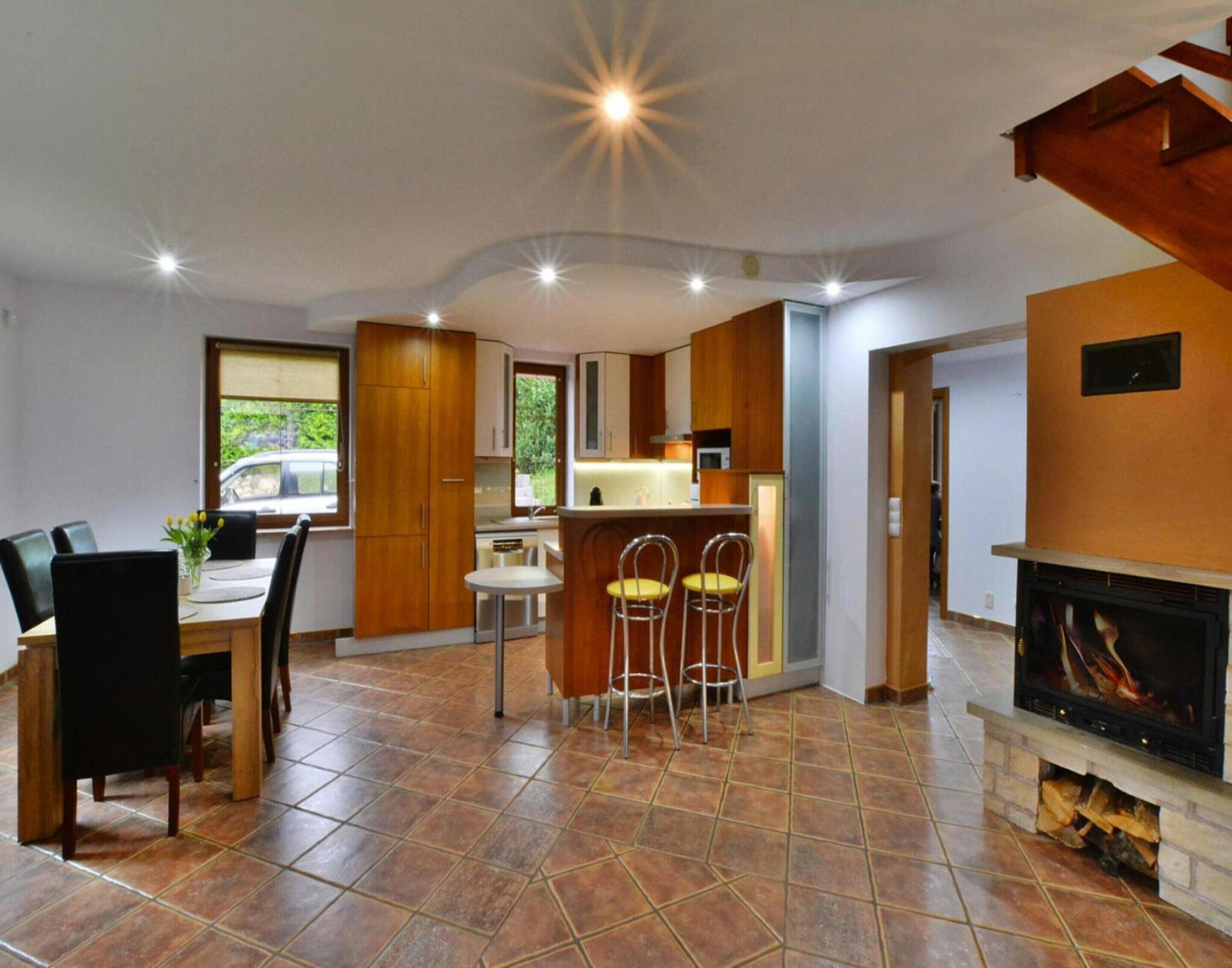 A modern kitchen with wooden cabinets, a dining area with a table and chairs, and a fireplace.