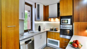 Une cuisine moderne dotée d’appareils électroménagers en acier inoxydable, de meubles en bois et d’un sol carrelé.