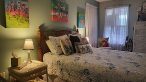Ein Schlafzimmer mit Bett, Nachttisch, Lampe, Stuhl und Kommode.