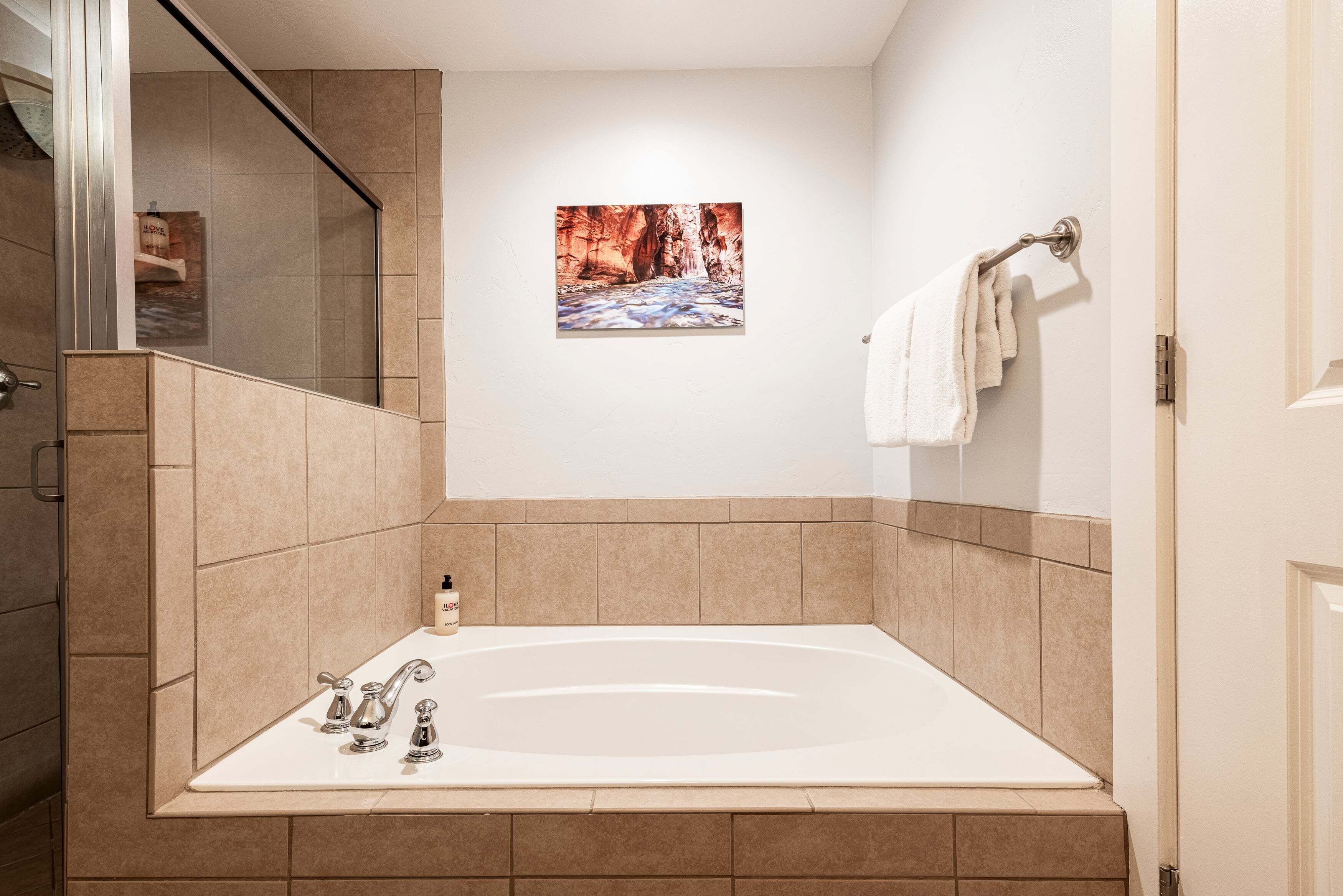 Een badkamer met een groot bad, een douche en een aan de muur hangend schilderij.