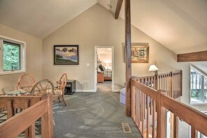 Une pièce spacieuse avec un plafond haut, un coin repas avec une table et des chaises, et une vue sur une chambre à coucher par une porte ouverte.