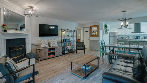 A modern living room with a fireplace, a television, and a dining area with a table and chairs. - Recently-renovated condo across from the Fox shuttle stop! (Angel Fire)