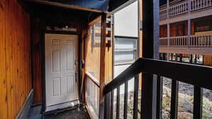 A wooden exterior with a 'Welcome' sign, a door, and a balcony with railings. - Recently-renovated condo across from the Fox shuttle stop! (Angel Fire)