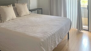 A bedroom with a bed, a ceiling fan, a nightstand, and a view through a window with curtains. - Modern, Peaceful Tempe Condo • Pool & Fast Wi-Fi (Tempe)