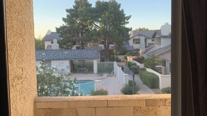 A balcony with a view of a residential area, a swimming pool, and a chair. - Modern, Peaceful Tempe Condo • Pool & Fast Wi-Fi (Tempe)
