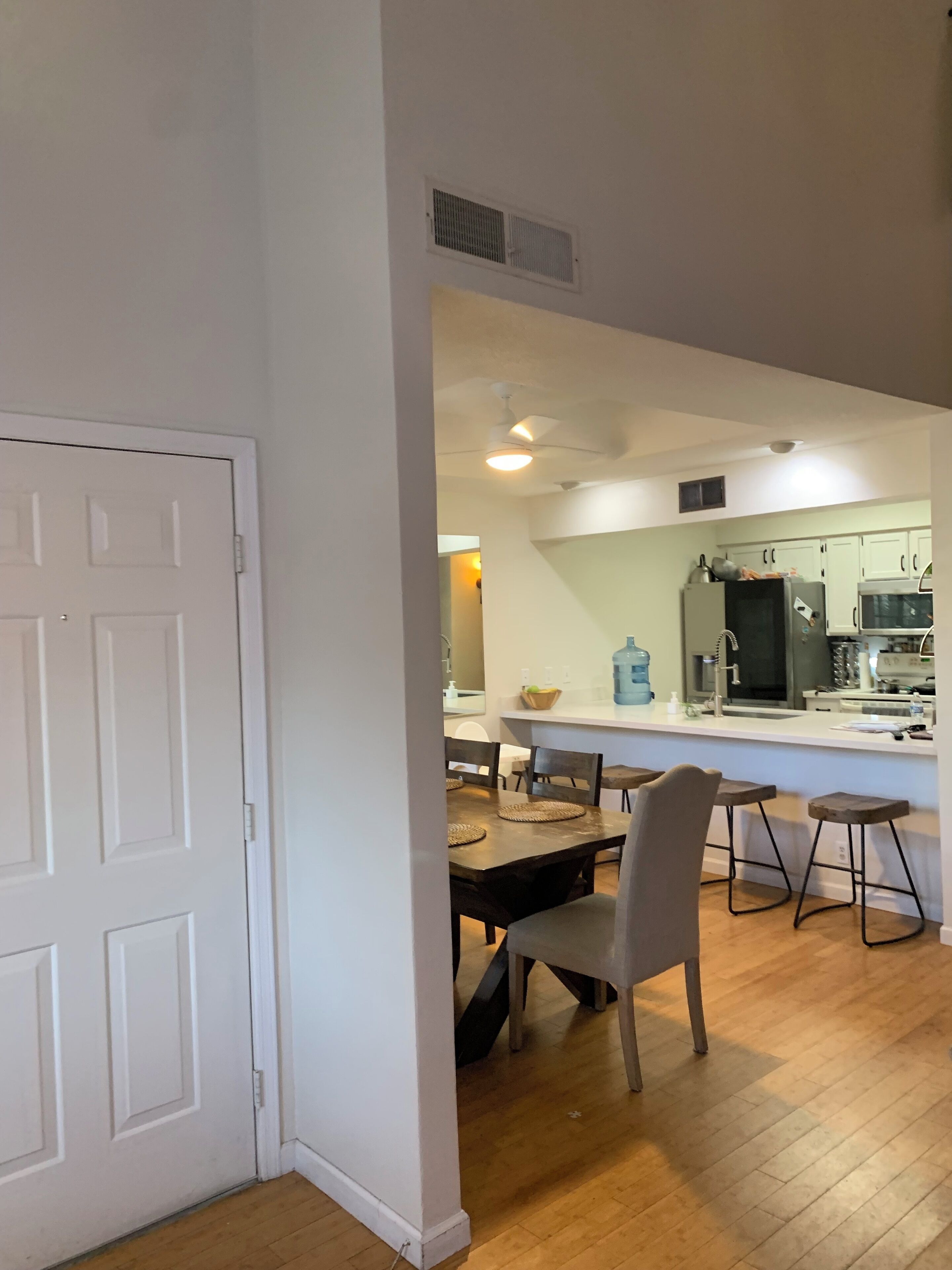 A modern kitchen with a central island, wooden flooring, and a dining area with a table and chairs.