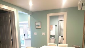 Un canapé d’angle beige, un tapis de couleur claire, une porte blanche et une salle de bain visible à travers une porte ouverte.