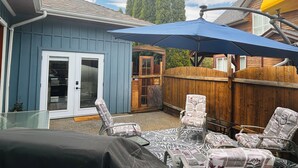 Un jardin avec une maison bleue, une clôture en bois et un patio couvert agrémenté de chaises à motifs.