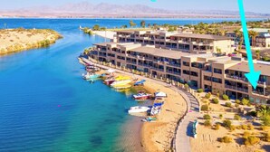 A coastal hotel with multiple balconies, a beach, and boats. It is located at the end of a channel, near a bridge, and has a gated community. - NEWLY REMODELED! 2bd, 2bath @Kingsview w.Beachfront View of the Channel (Lake Havasu City)