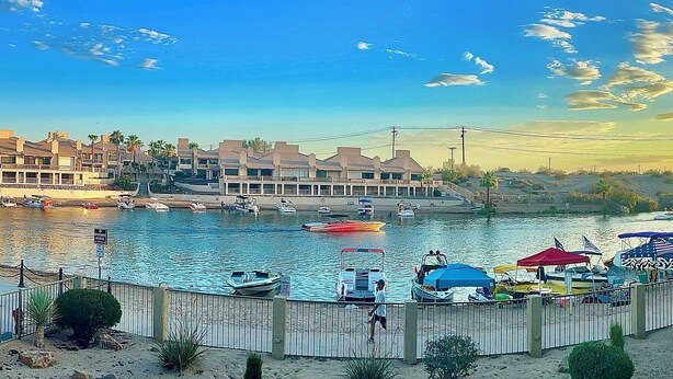 A waterfront hotel with a river view, a bridge in the background, and boats docked near the shore. - NEWLY REMODELED! 2bd, 2bath @Kingsview w.Beachfront View of the Channel (Lake Havasu City)
