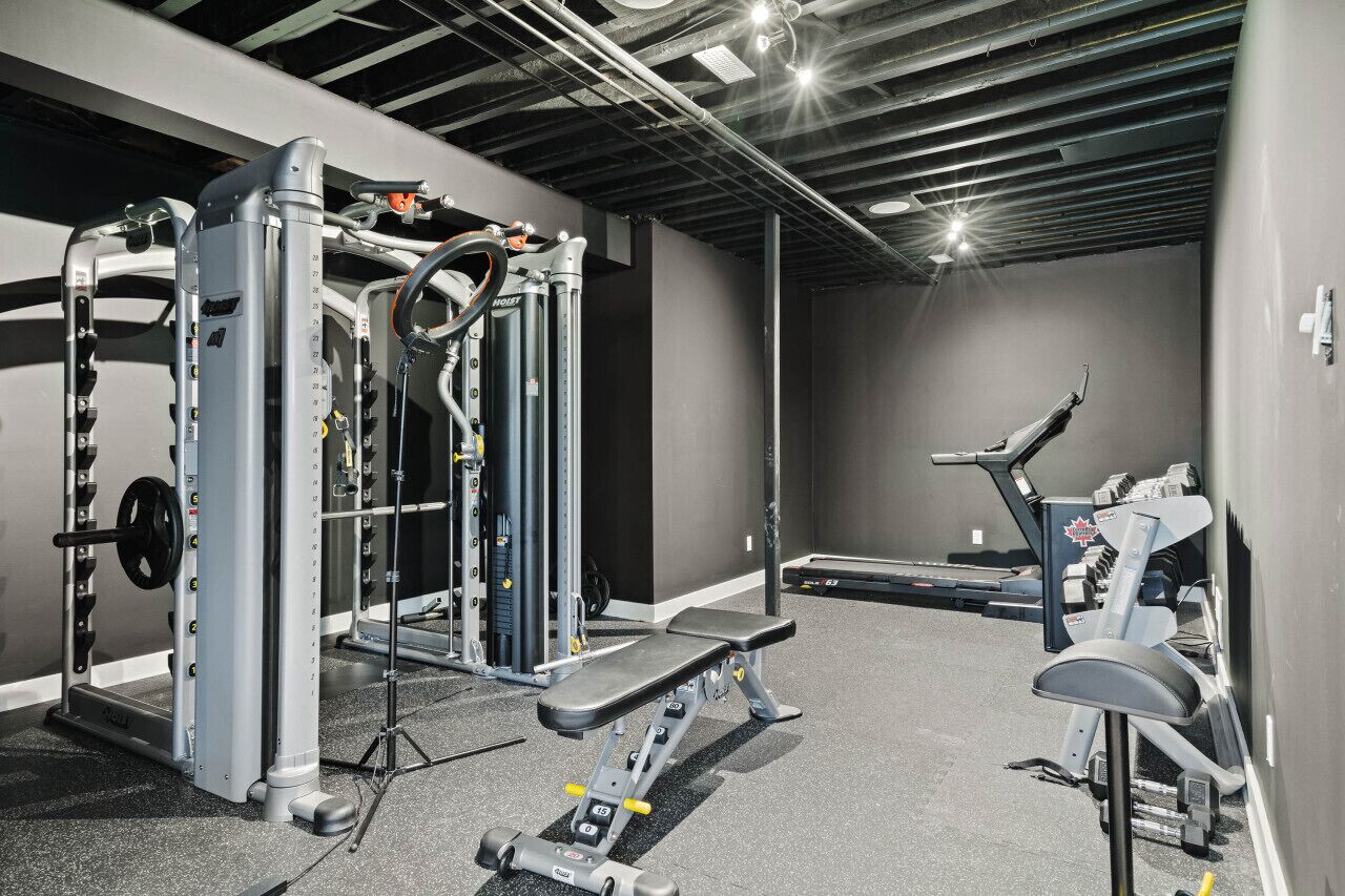 A gym with weightlifting equipment, treadmills, and a bench.
