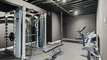 A gym with weightlifting equipment, treadmills, and a bench.