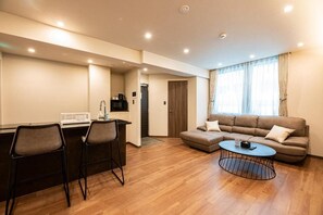 Una sala moderna con un sofá, una mesa de centro y un comedor con sillas y una pequeña cocina.