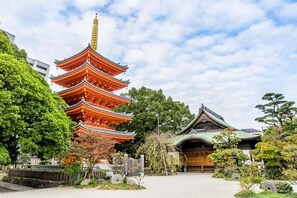 A traditional Japanese pagoda with multiple tiers, surrounded by lush greenery and a well-maintained garden. - Axion Hotels Tenjin (Fukuoka)