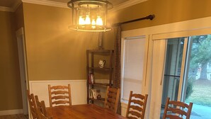 A dining room with a wooden table and chairs, a chandelier, a bookshelf, and a window with blinds. - Country Feel but close to town, Dunn Rite Ranch House (Nampa)
