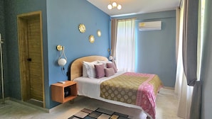 Ein Schlafzimmer mit Bett, Nachttisch, Wanddekoration und Klimaanlage.