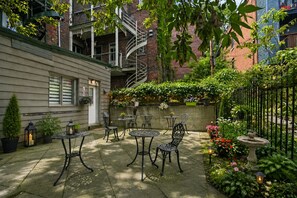 Une cour avec des espaces amĂ©nagĂ©s pour sâasseoir Ă lâextĂ©rieur, un escalier et diverses plantes.