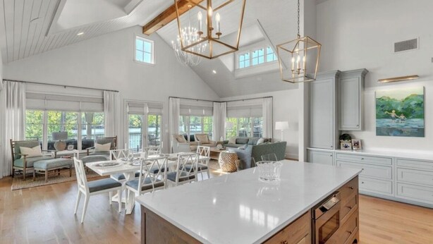 A spacious living area with a large dining table, multiple seating options, and a kitchen island. - Experience Ultimate Relaxation: Stunning Lakeside Retreat (Dadeville)