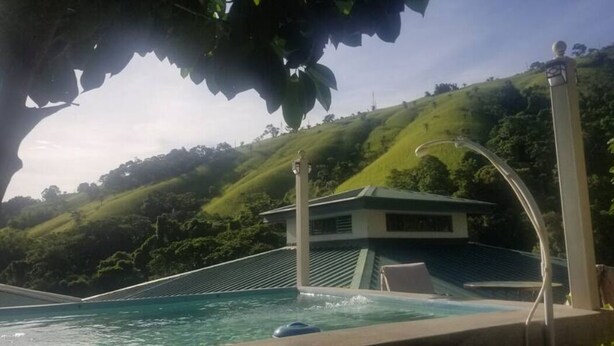 Área da piscina com vista para uma colina e um edifício ao fundo.