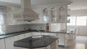A kitchen with white cabinets, a black countertop island, and a tiled floor. - Birch house (San Vicente del Raspeig)