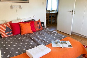 A bed with a star-patterned bedspread, a white towel, and an open magazine on an orange blanket.