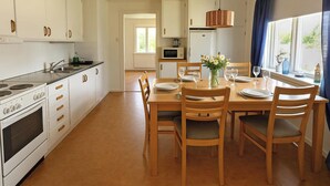 Una cucina con mobili bianchi, un fornello e un tavolo da pranzo per quattro persone, completo di sedie.