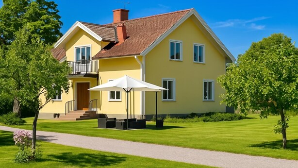 Una casa a due piani con un balcone, vialetto in pietra e un prato curato.