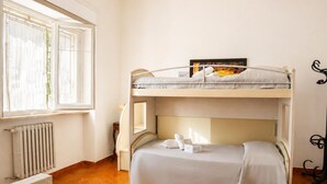 Habitación con literas, un radiador, una ventana y una silla.