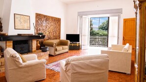 Una sala de estar con chimenea, televisión y vistas al exterior.