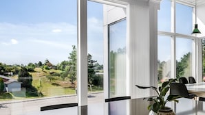 A modern kitchen with a large island, white cabinetry, and a view of a garden and neighboring houses. - "Jonce" - 800m from the sea by Interhome (Ebeltoft)