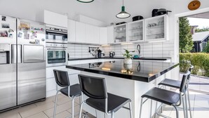 A modern kitchen with stainless steel appliances, a central island with bar stools, and a view of the outdoors. - "Jonce" - 800m from the sea by Interhome (Ebeltoft)