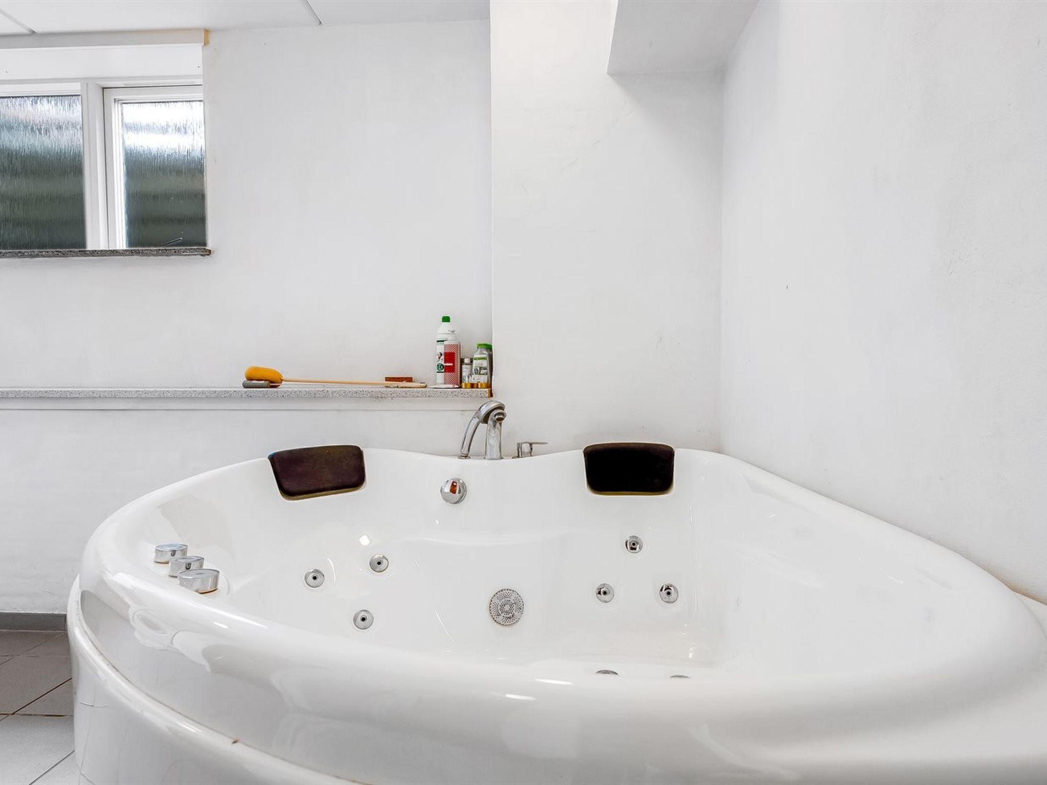 A modern bathroom with a freestanding bathtub, a window, and a shelf with toiletries.