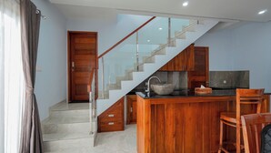 Una cocina moderna con una isla de madera, un lavaplatos empotrado y una escalera de cristal.