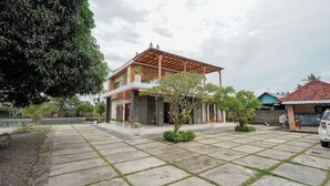 Una casa de dos pisos con un porche cubierto, una piscina y un jardín con diversas plantas.