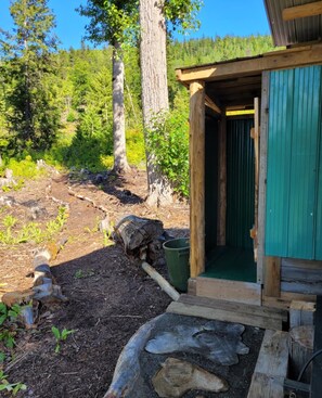 A rustic cabin with a green door and a wooden porch.