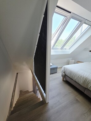 A bedroom with a skylight, a bed, and a staircase leading to an upper floor. - Renovated house 300 m from the beach and the GR34 (Landéda)