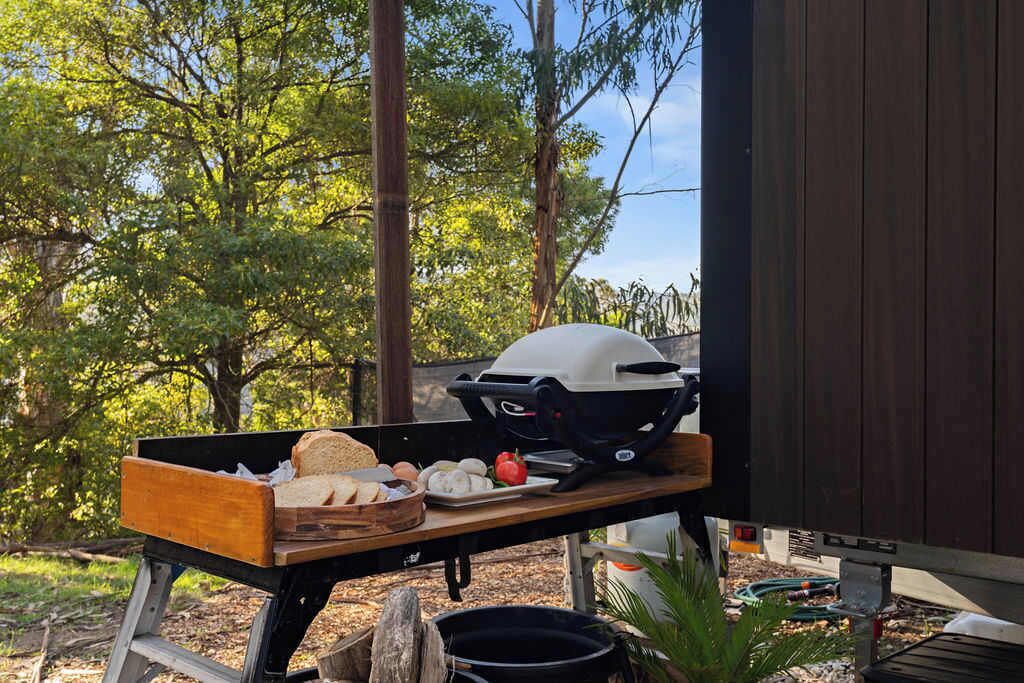 Un barbecue avec des aliments disposés sur une table en bois, à l’extérieur.