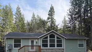 A two-story house with a front porch and a garage, surrounded by tall trees. - Dacha in Hoodsport w/Hot tub (Hoodsport)